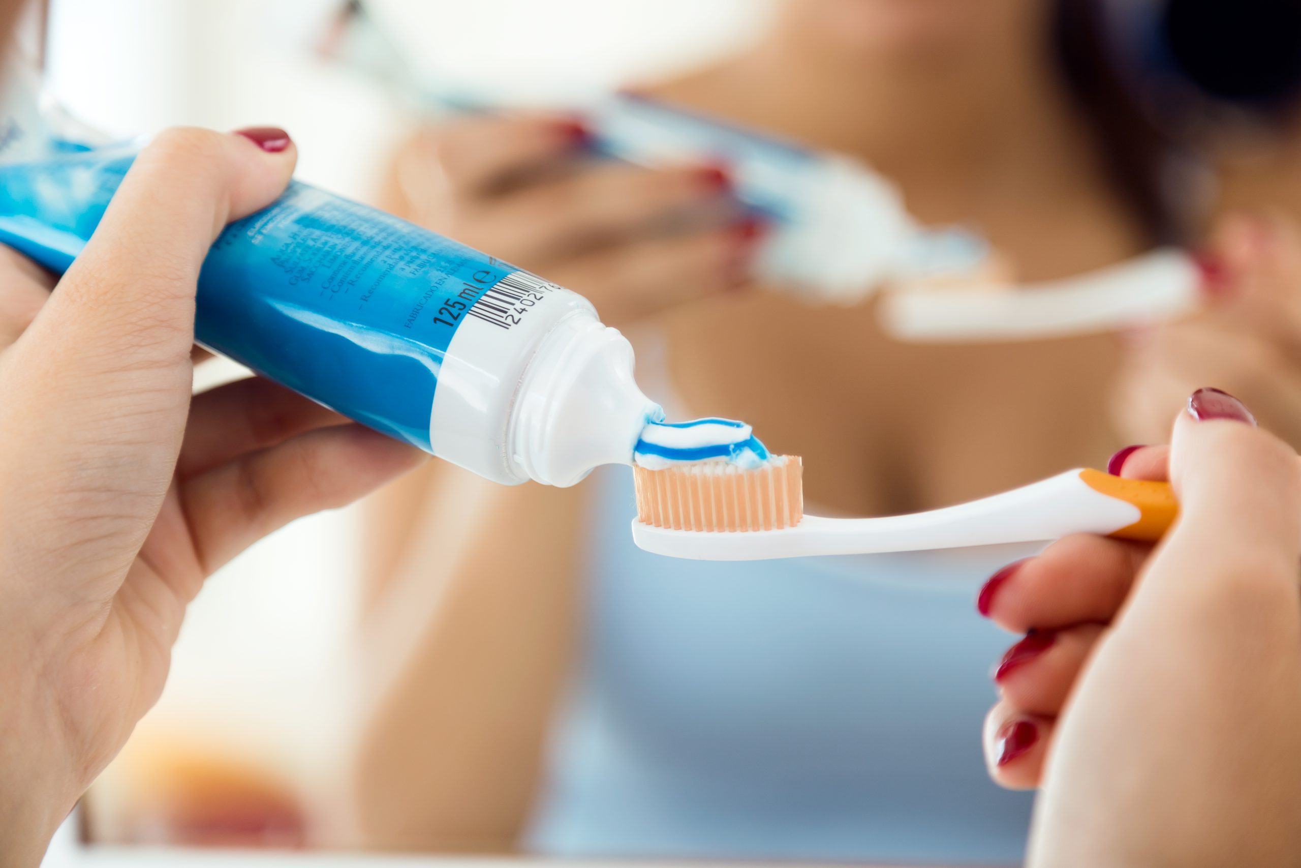 Femme mettant du dentifrice sur ça brosse à dent pour une bonne hygiène dentaire